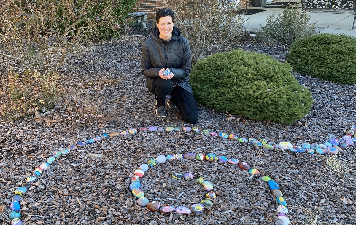 Garner poses by the rock garden created from the Academy's Identity Rock Art Project. Photo by Amie Snow