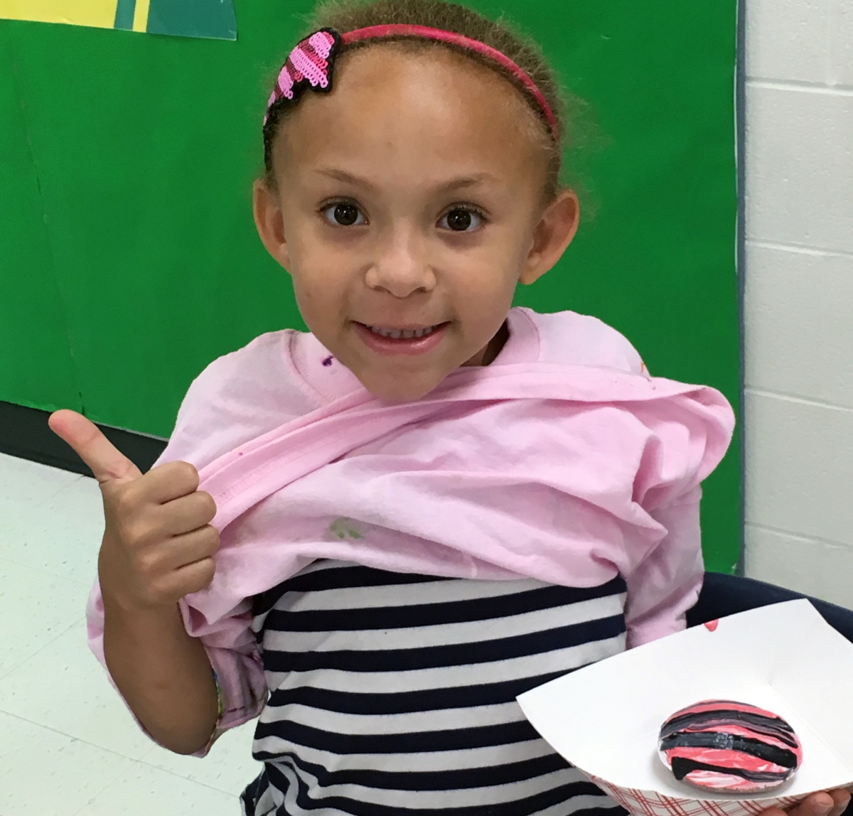 Academy first grader, Kaylee Simmons, shows off her rock painted with the same colors and pattern of the shirt she was wearing that day. Photo submitted