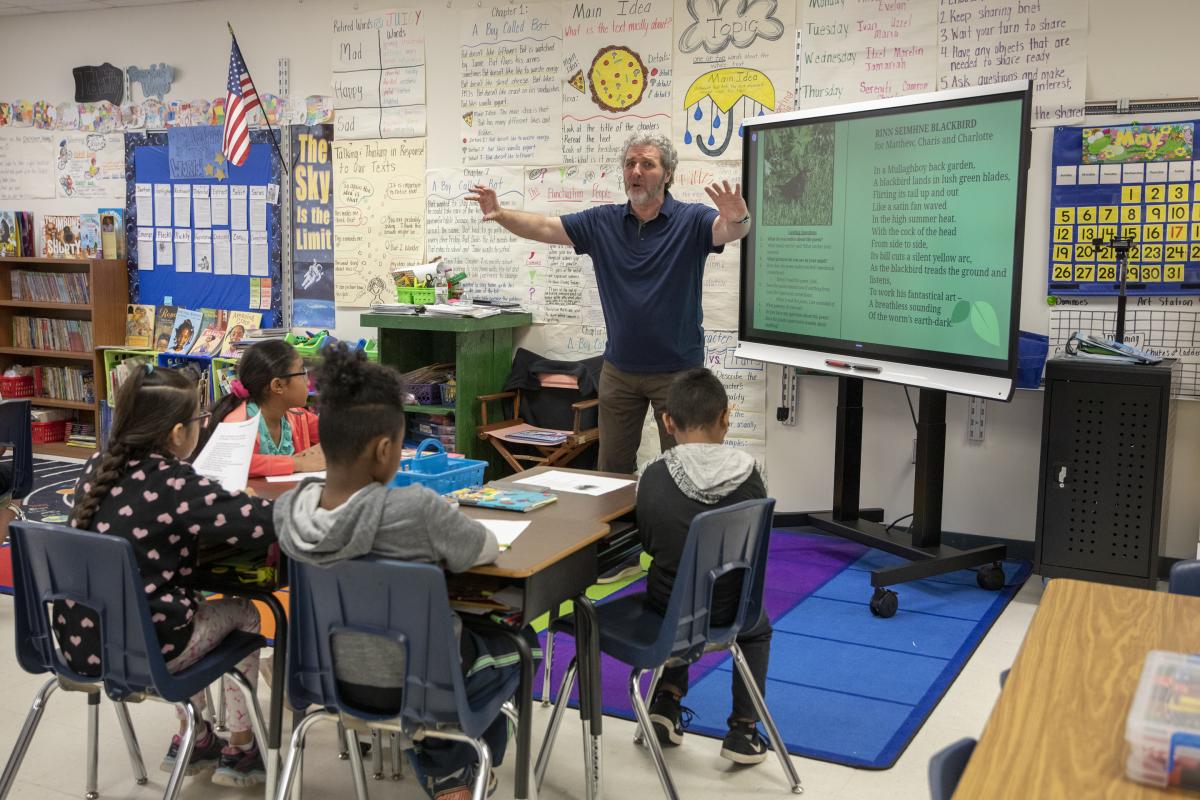 Rice shares and acts out his poem, “Rinn Seimhne Blackbird.” Academy third-grade students eagerly watch. Photo by Troy Tuttle