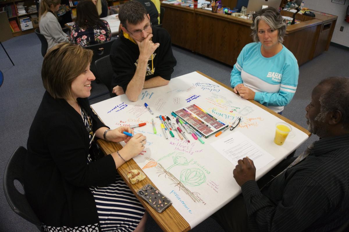 From left to right: Snow ‘06 ‘14, 2nd grade teacher Brent Macrow, 1st grade teacher Marla Cantrell, and Hunter discuss community resources that would assist in the construction of a school garden at the Academy. Photo by Vachel Miller